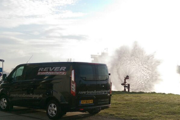 Flowmeting van een brandkraan naast een servicevoertuig van Rever Brandbeveiliging.